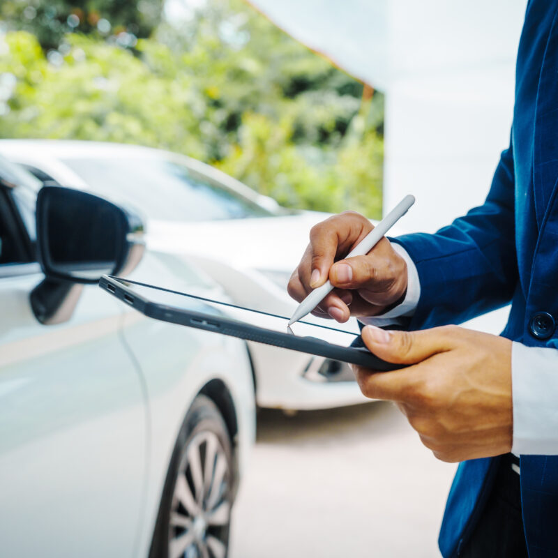 Preparación para su consulta de abogado de accidente de coche de Dallas. Hombre de negocios en traje y auto agente de seguros evaluar los daños del coche, discutiendo deducible, reclamaciones, opciones de cobertura a todo riesgo y seguro de colisión, completando los formularios necesarios y las evaluaciones.