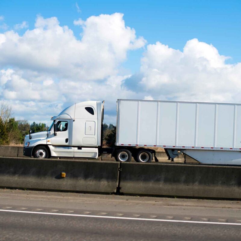 Camión blanco circulando por la autopista, mostrando las rutas de transporte por carretera más peligrosas de Dallas.