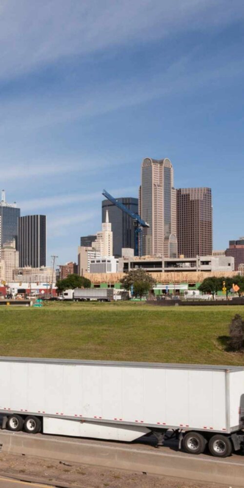Semi truck near Dallas skyline showing what are the most dangerous trucking routes in Dallas