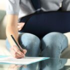 Woman with arm sling signing documents, illustrating factors influencing personal injury case value.