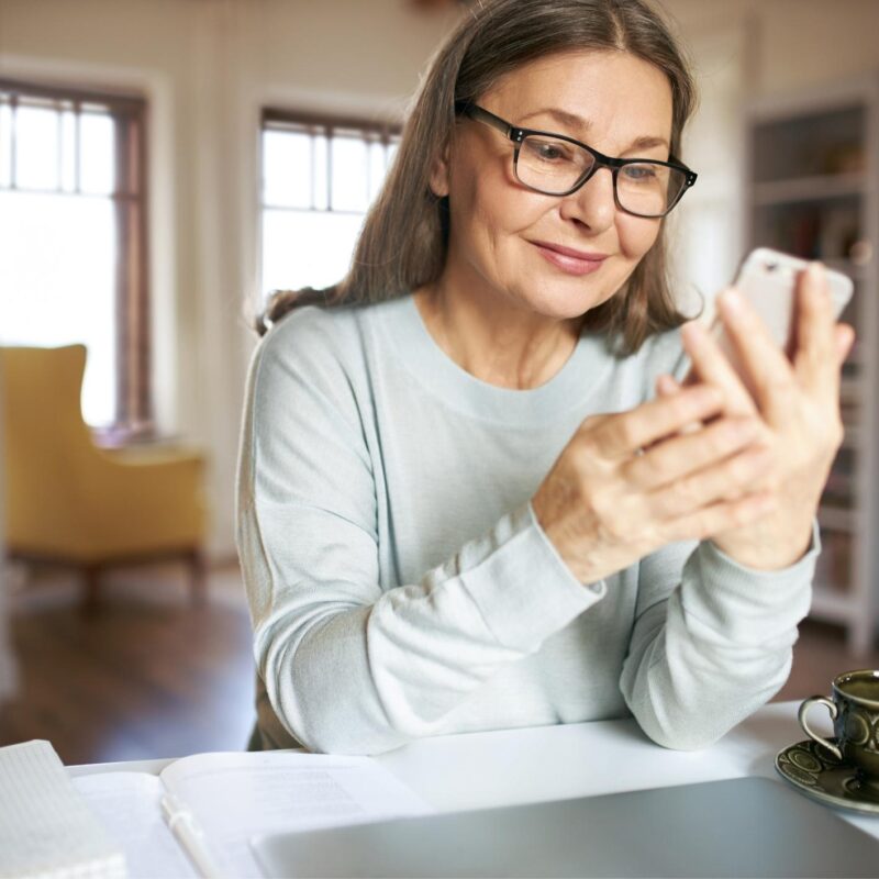 Mujer usando su celular en una mesa, ilustrando una investigación legal sobre lesiones personales realizada con ChatGPT.